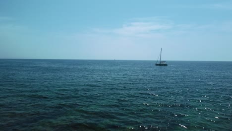 A-vacation-catamaran-sailing-ship-boat-in-a-blue-clear-water-seaside-bay-in-the-idyllic-Adriatic-mediterranean-sea-ocean-close-to-the-Croatian-coast-with-blue-sky