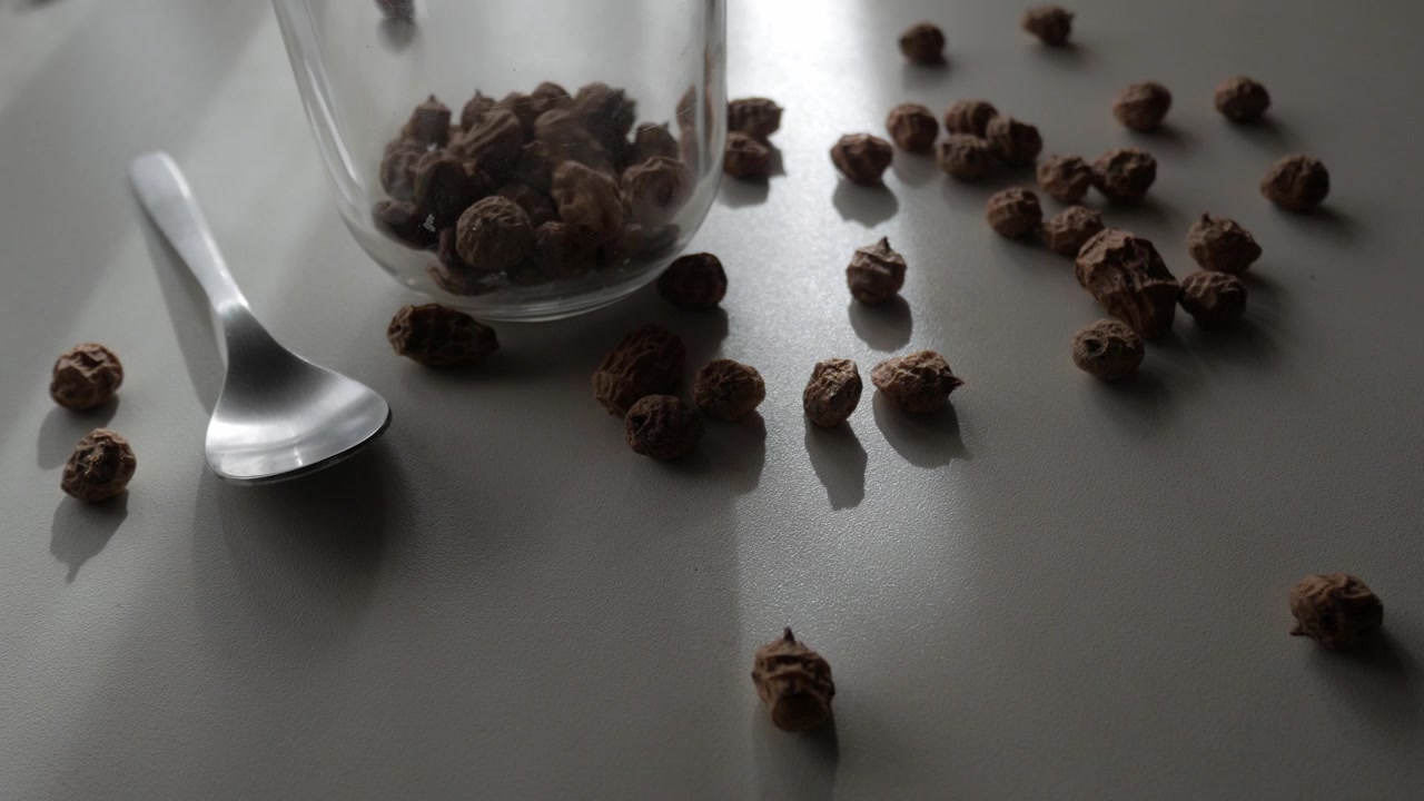 Chufa secca versata in un barattolo di vetro accanto a un cucchiaio su un tavolo da cucina