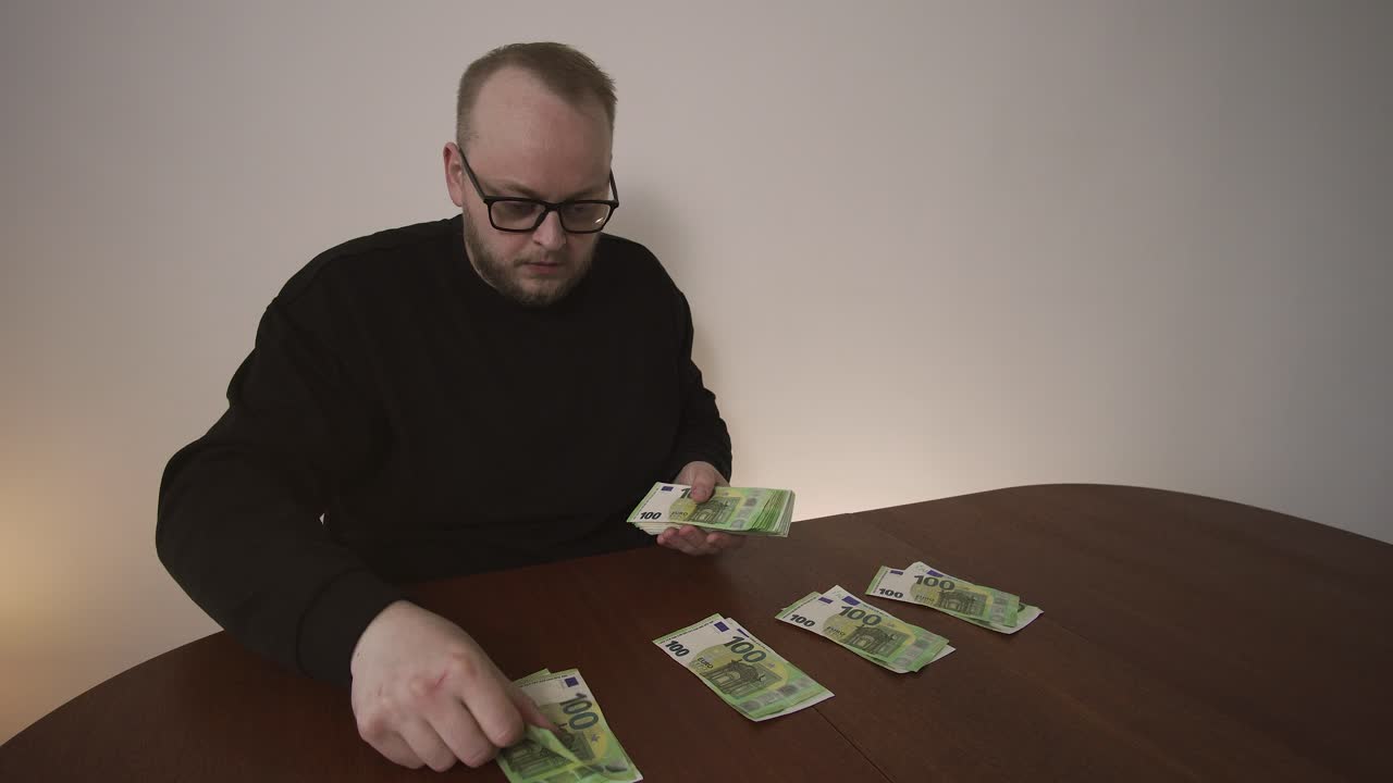 Uomo che divide banconote in euro in pile per diverse spese a casa. Concetto di bilancio, pianificazione degli acquisti e gestione delle finanze personali