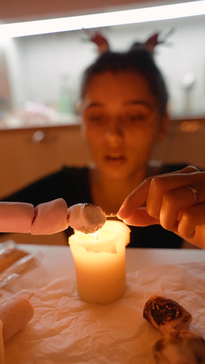 Woman roasting marshmallows over a candle flame