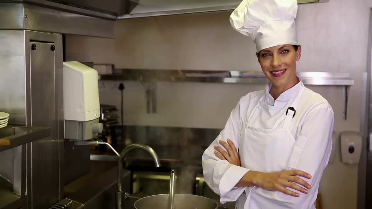 Bella chef in piedi accanto a una grande pentola fumante