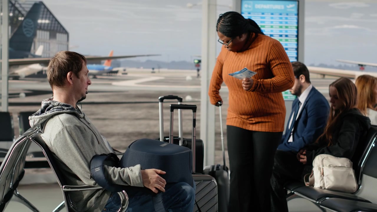 Woman in busy airport sitting down on chair, waiting for plane