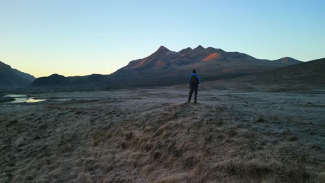 slow anticlockwise pan of hiker against black cuillin mountains at dawn on the isle of skye scotland