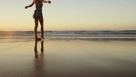 Woman-with-arms-outstretched-walking-on-beach