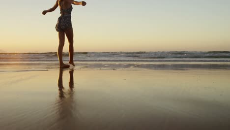 woman with arms outstretched walking on beach