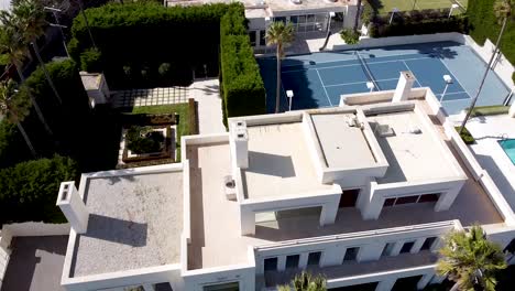 aerial - drone shot of luxury mansion with tennis court and pool