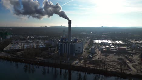 waste to energy plant emitting smoke from its chimney, located near an urban area, environmental impact of waste. stunning aerial view flight ascending drone