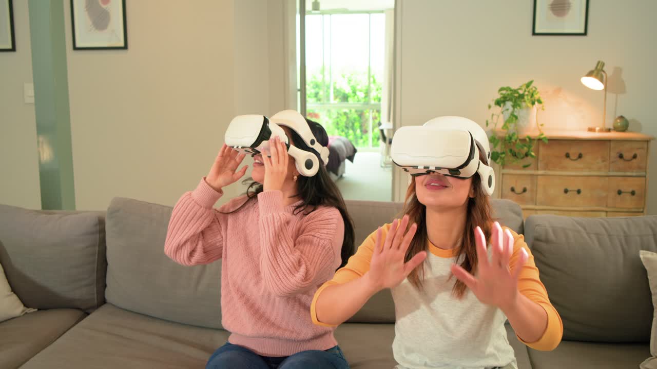 Dopo aver indossato i visori VR, diverse amiche esplorano il mondo della realtà virtuale su un divano in soggiorno