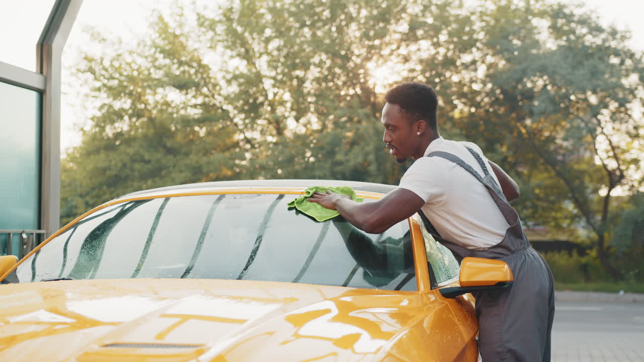hombre lavando un coche amarillo en un lavado de coches