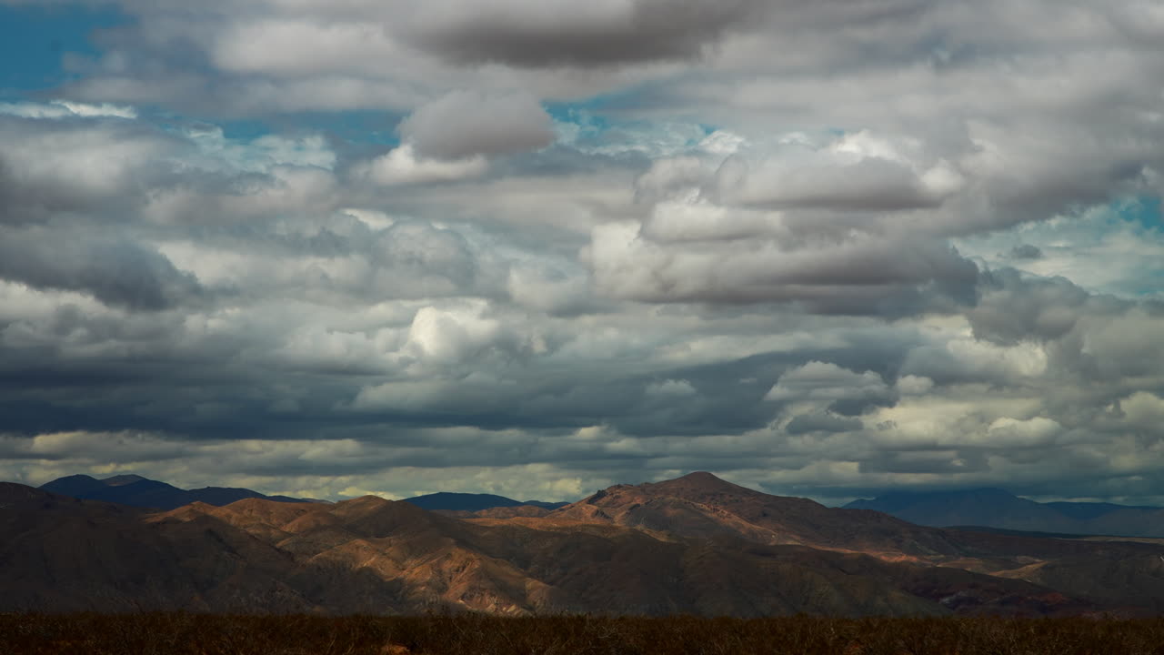 paisaje nuboso diurno lapso de tiempo sobre las montañas más allá de la cuenca del desierto de mojave
