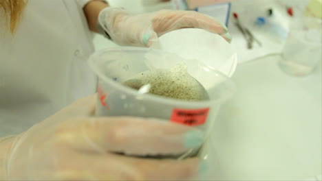 in a science laboratory, a scientist pours waste water through a filter for analysis purposes