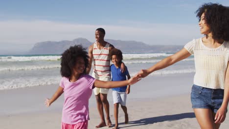 Lächelnde-Afroamerikanische-Eltern-Und-Ihre-Kinder-Gehen-Händchen-Haltend-Und-Umarmend-Am-Strand-Spazieren