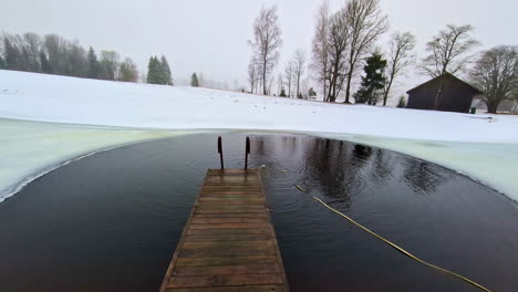 Wunderschöne-Aufnahme-Einer-Wasserquelle-Mitten-Im-Eis,-Mit-Einem-Kleinen-Dock-Und-Einer-Leiter