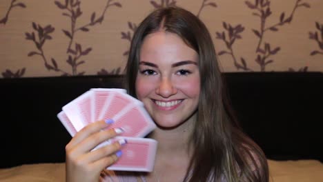 Girl-messing-around-while-playing-cards,-gives-a-wink