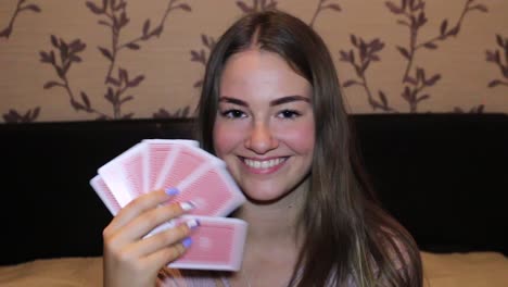 chica jugando mientras juega a las cartas, hace un guiño