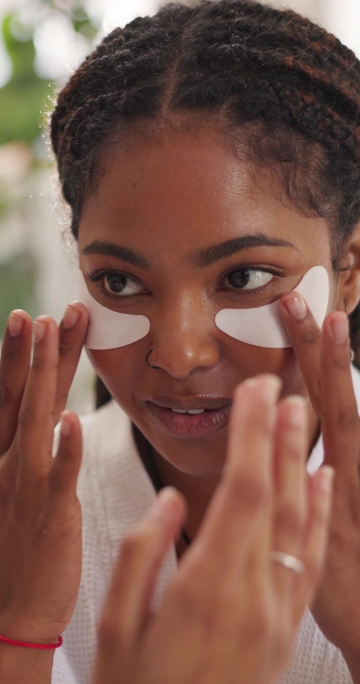 Young Woman Applying Under-Eye Patches in Mirror
