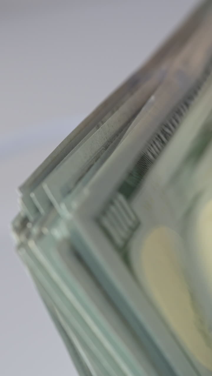 Quickly counted one hundred dollar bills in money counting machine. Rotating mechanism of equipment close up. Blurred backdrop. Vertical video
