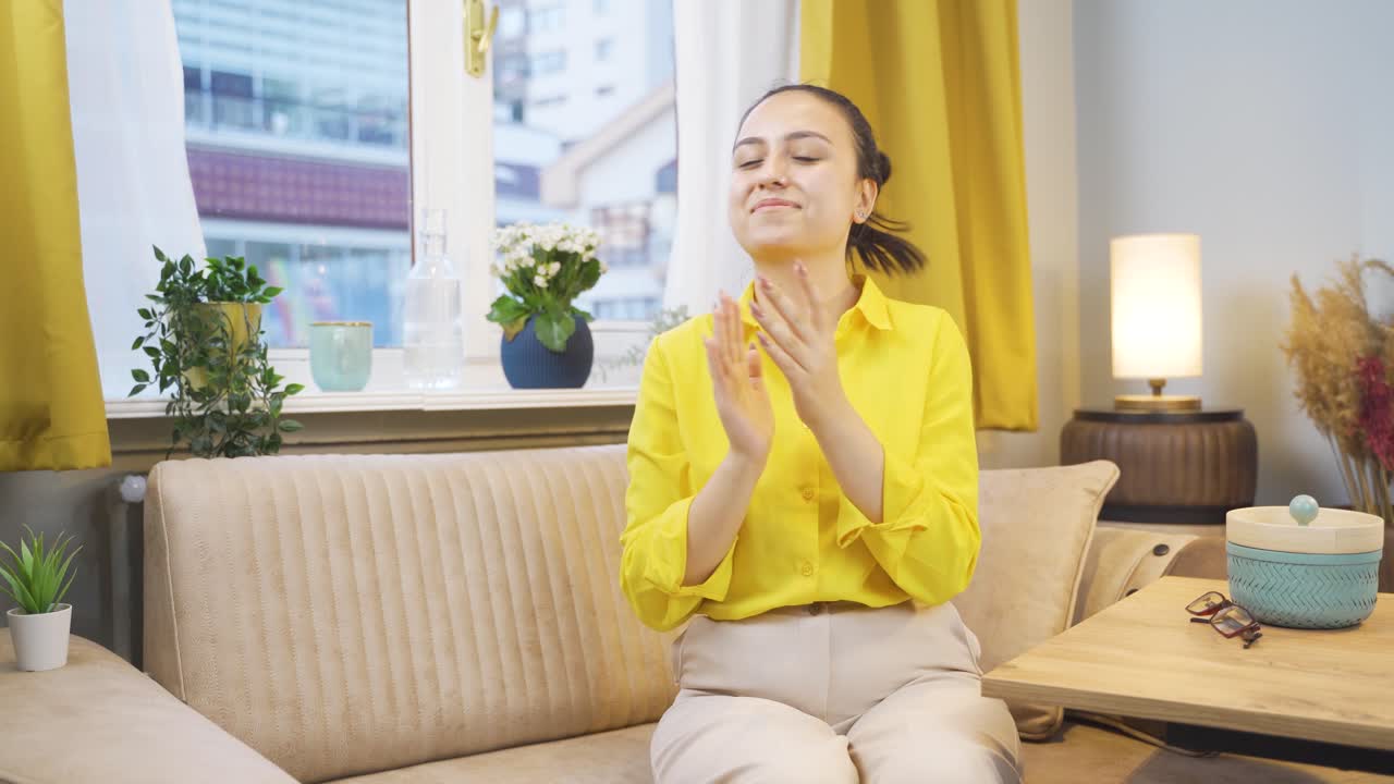 젊은 여성이 카메라에 축하 메시지를 보내며 박수를 치고 있습니다.