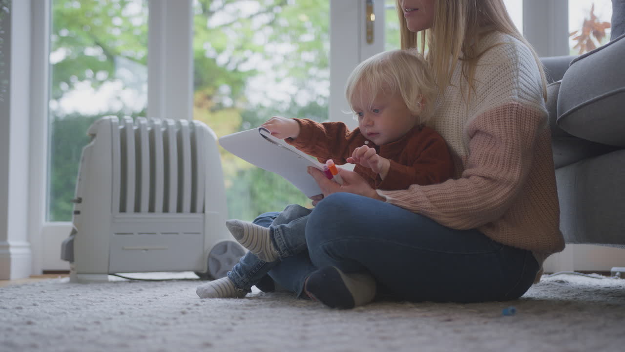 생활 비용 에너지 위기 동안 집에서 그림을 그리는 라디에이터 플러그를 가진 어머니와 아들