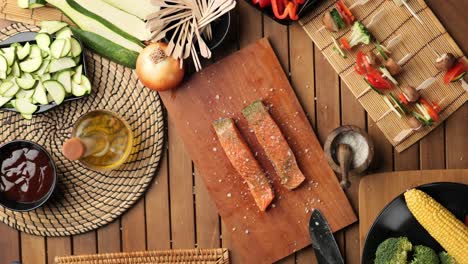 top down shoot of salmon lying on a wooden board surrounded by ingredients