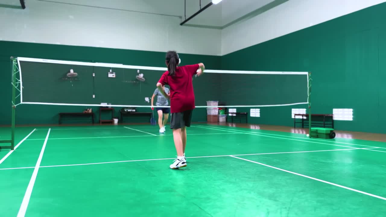 Two Women Playing Badminton in an Indoor Court