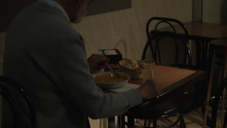 elderly man eating soup in a restaurant