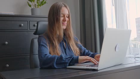 Mujer-Corporativa-Sonriente-Escribiendo-En-Una-Computadora-Portátil-En-Una-Acogedora-Oficina-En-Casa