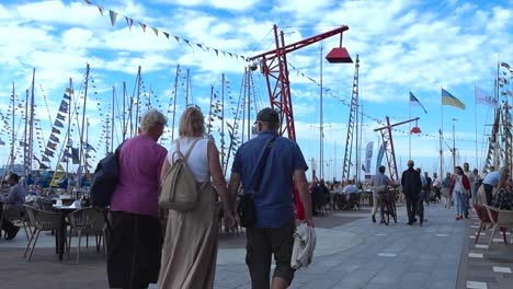 Vibrant Marina Promenade with Flag-Draped Sailboats and Outdoor Cafes
