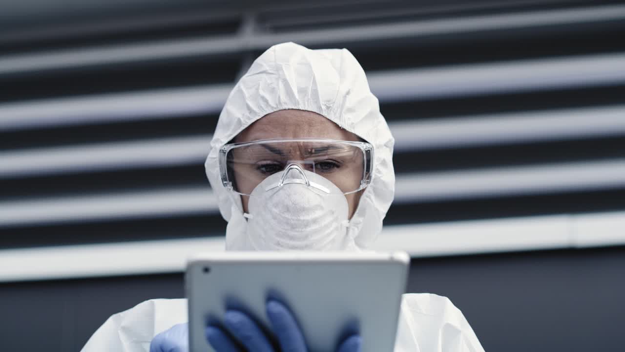 Video di un tecnico in tuta sterile e con un tablet