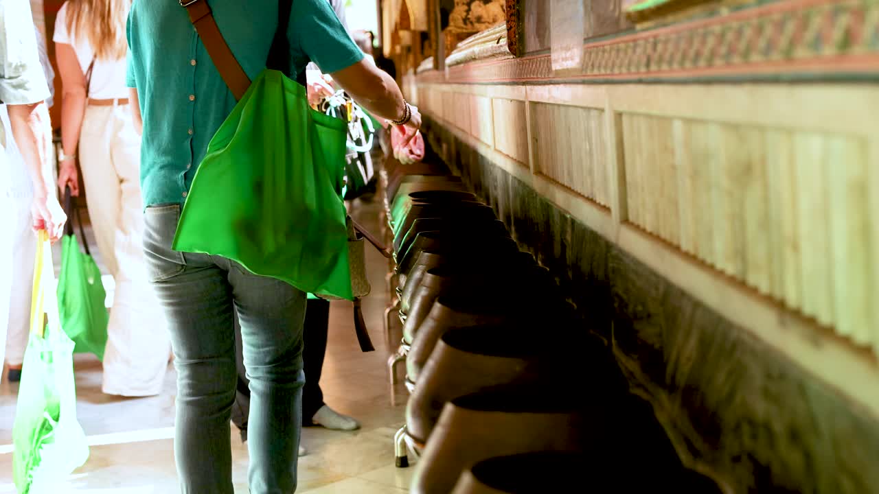 방 의 포 사원 에서 동전 을 그 에 넣고 있는 관광객