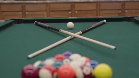 billiards pool table with crossed pool cues in a game room