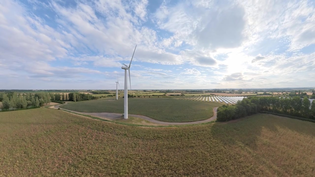 aerial drone footage, Sunset view over a field of renewable energy sources featuring wind turbines and natural scenery. Lincolnshire solar panel arrays wind turbines countryside, England