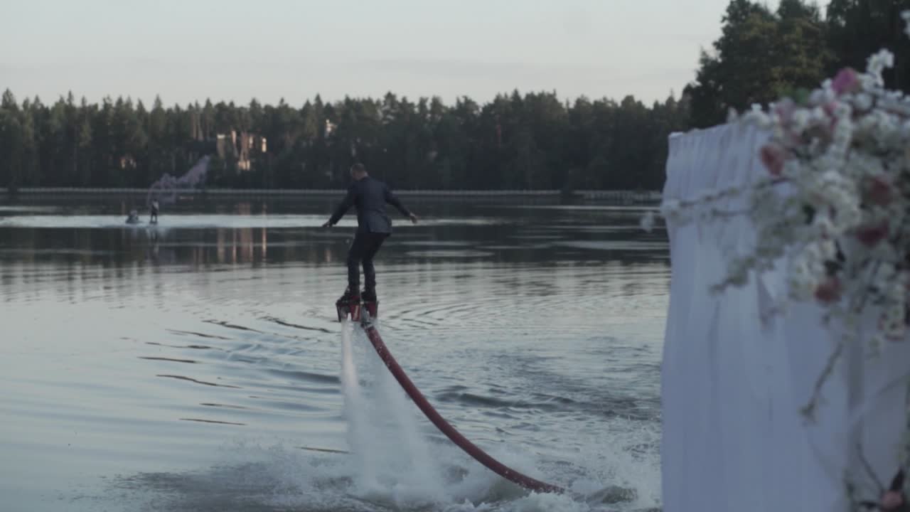 옷 입은 남자가 호수에서 플라이보드를 타고 있다