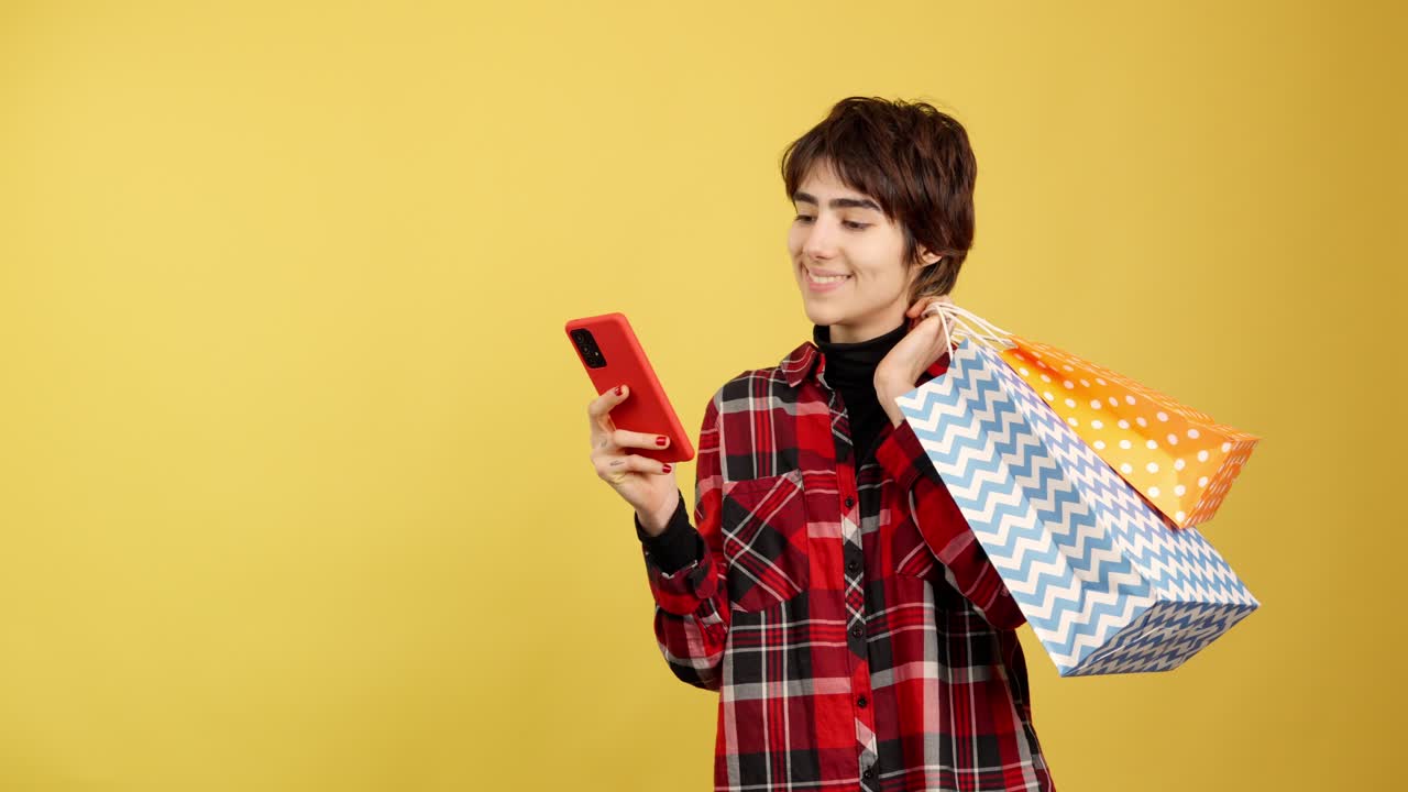 Young woman shopping online with smartphone and bags