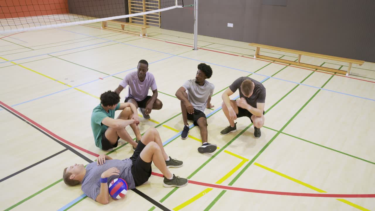 Fünf männliche Teamkollegen halten einen Volleyball nahe des Netzes, versammeln sich und inspizieren den Ball auf dem Sportplatz.