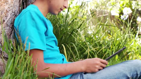 Cute-boy-listening-to-music-with-headphones-sitting-on-the-grass