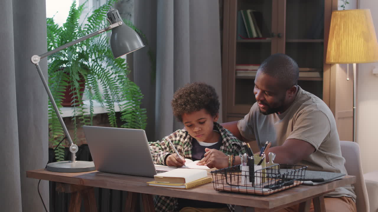 Afro-American Man And Little Son Doing Homework Together