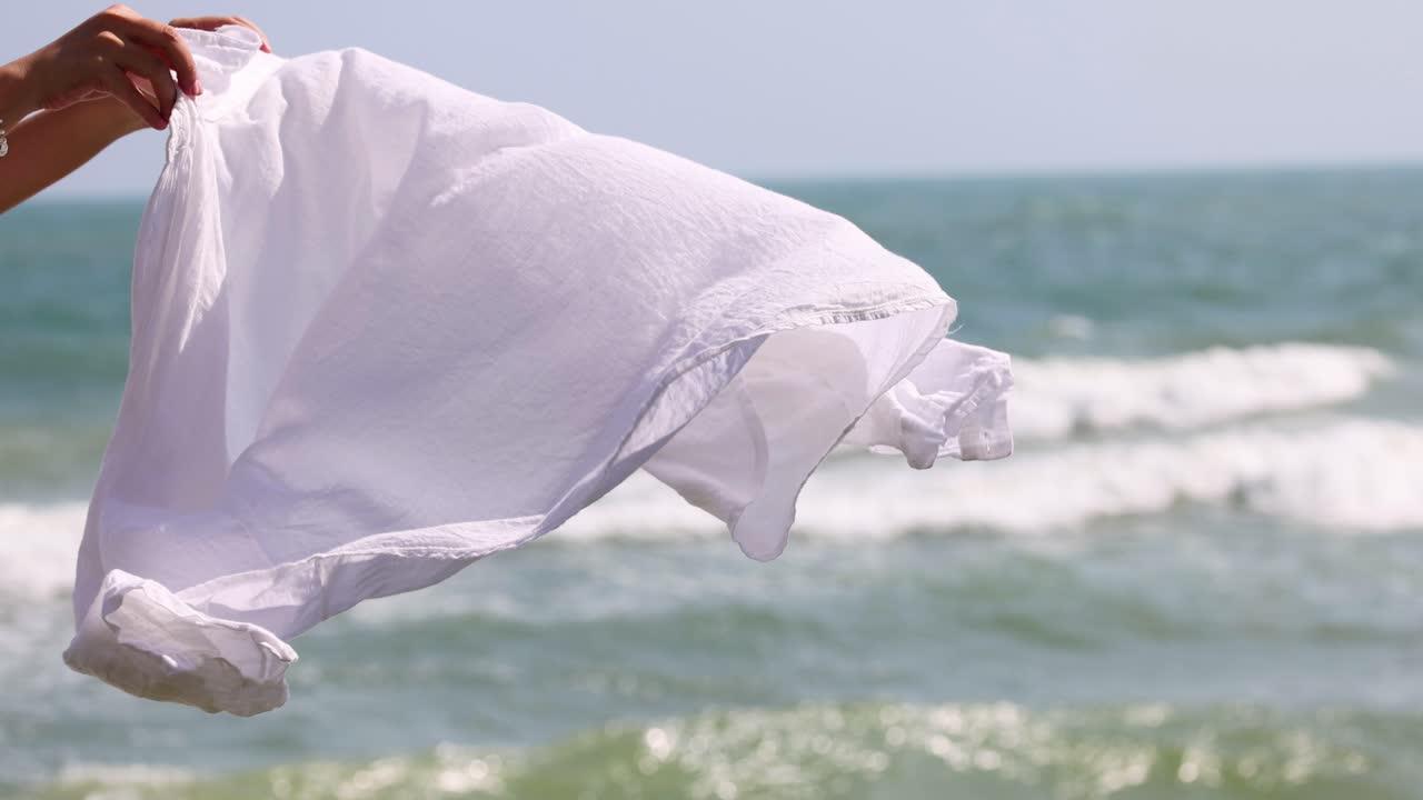 바다의 물결을 배경으로 색 시트가 흔들리고 있습니다.