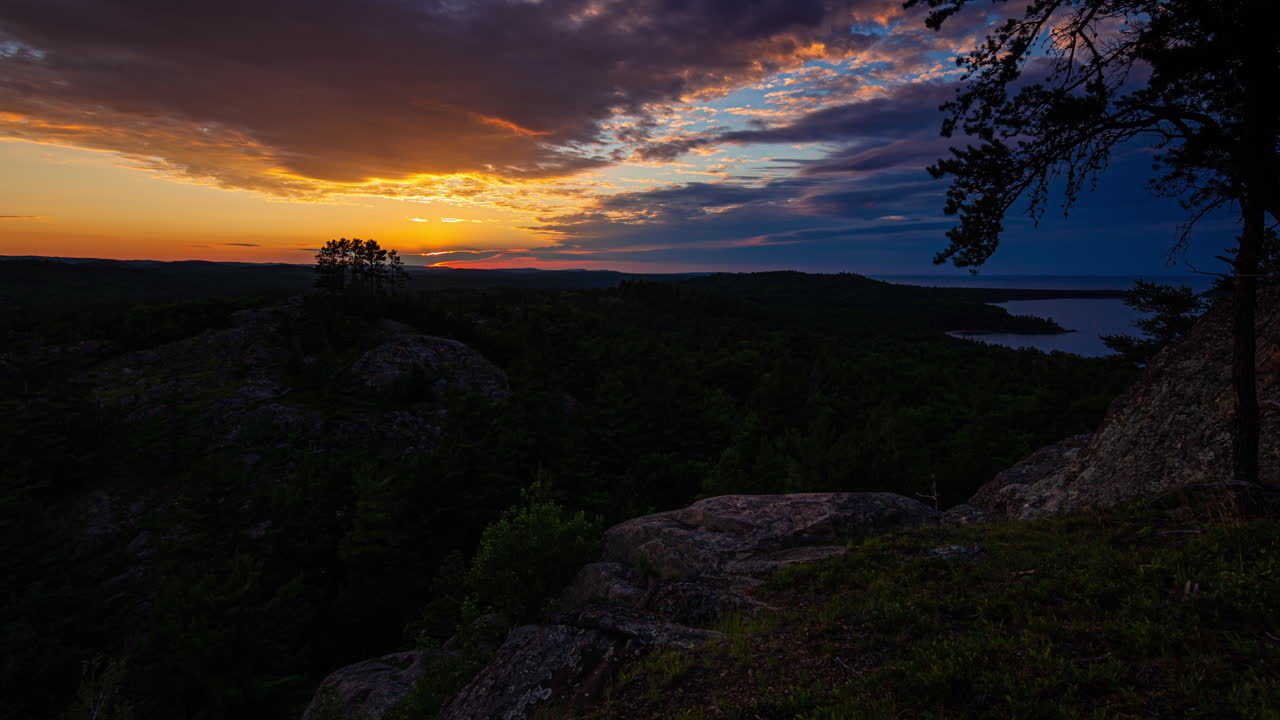 Timelapse de um pôr do sol dourado brilhante sobre as florestas da Península Superior de Michigan, filmado na margem do Lago Superior em 4K