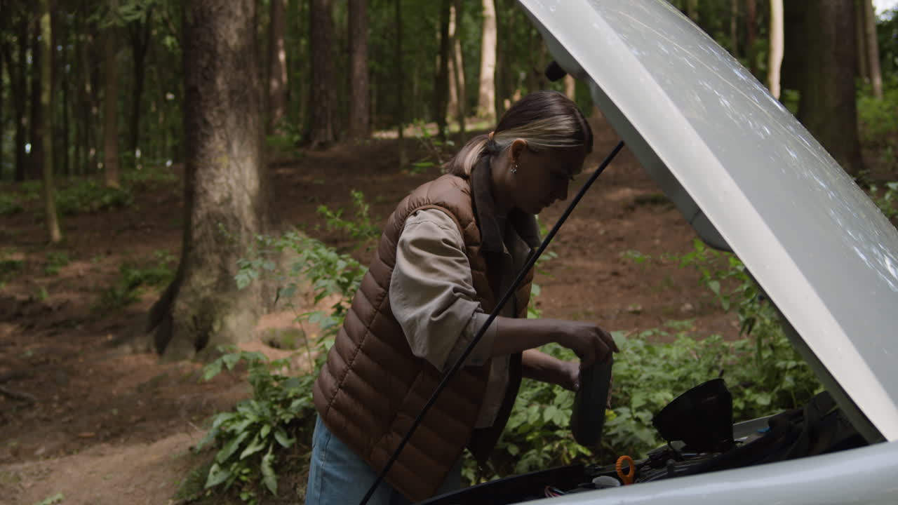 Woman doing car maintenance in a forest
