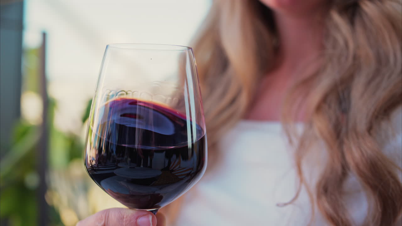Close up of a woman swirling a glass of red wine at a terrace