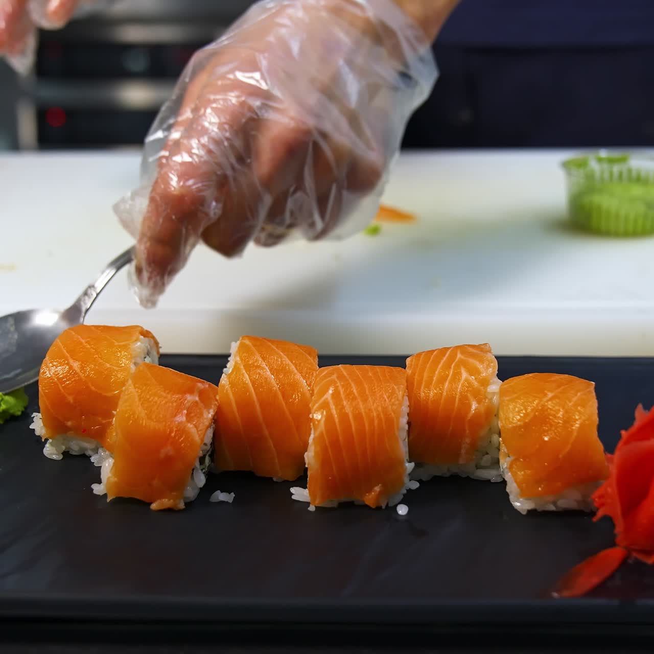 Professional chef hand decorate sushi roll on a serving plate to custom. Chef preparing delicious sushi menu fish with rice in japanese restaurant