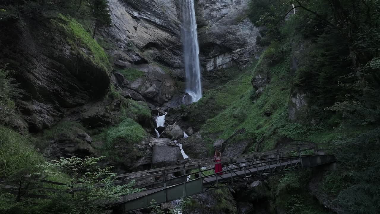 una persona está de pie en un puente debajo de la cascada en berschis, st.