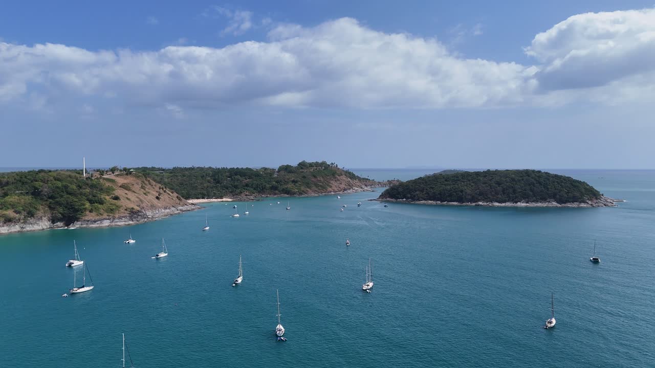 드론 영상은 태국 푸켓 근처의 조용한 만에서 항해하는 요트를 포착합니다. 은 하늘과 조용한 물을 보여줍니다.
