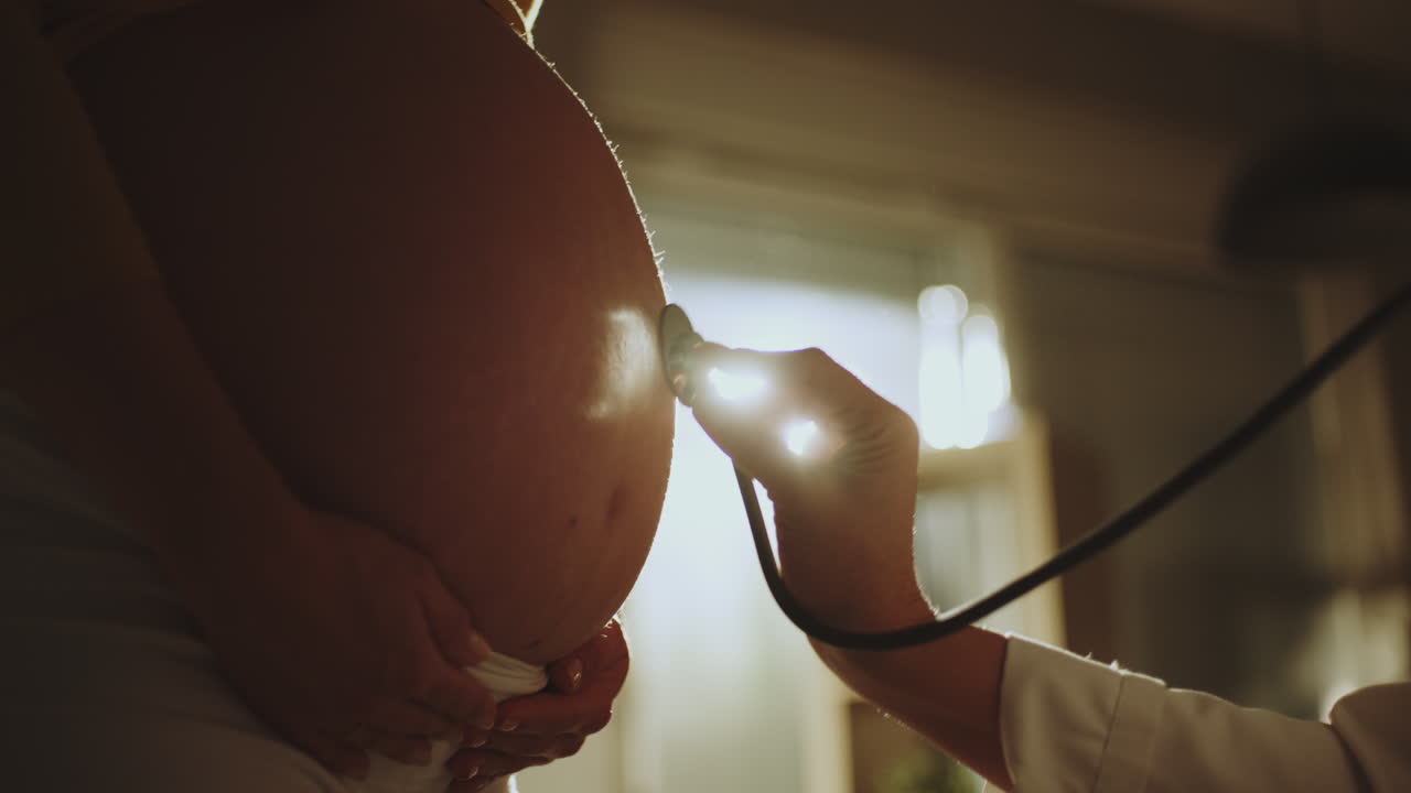 Doctor examining pregnant woman's belly with stethoscope