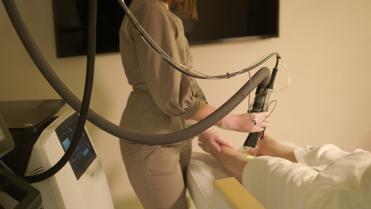 Cosmetologist Performing Laser Hair Removal on Woman's Leg