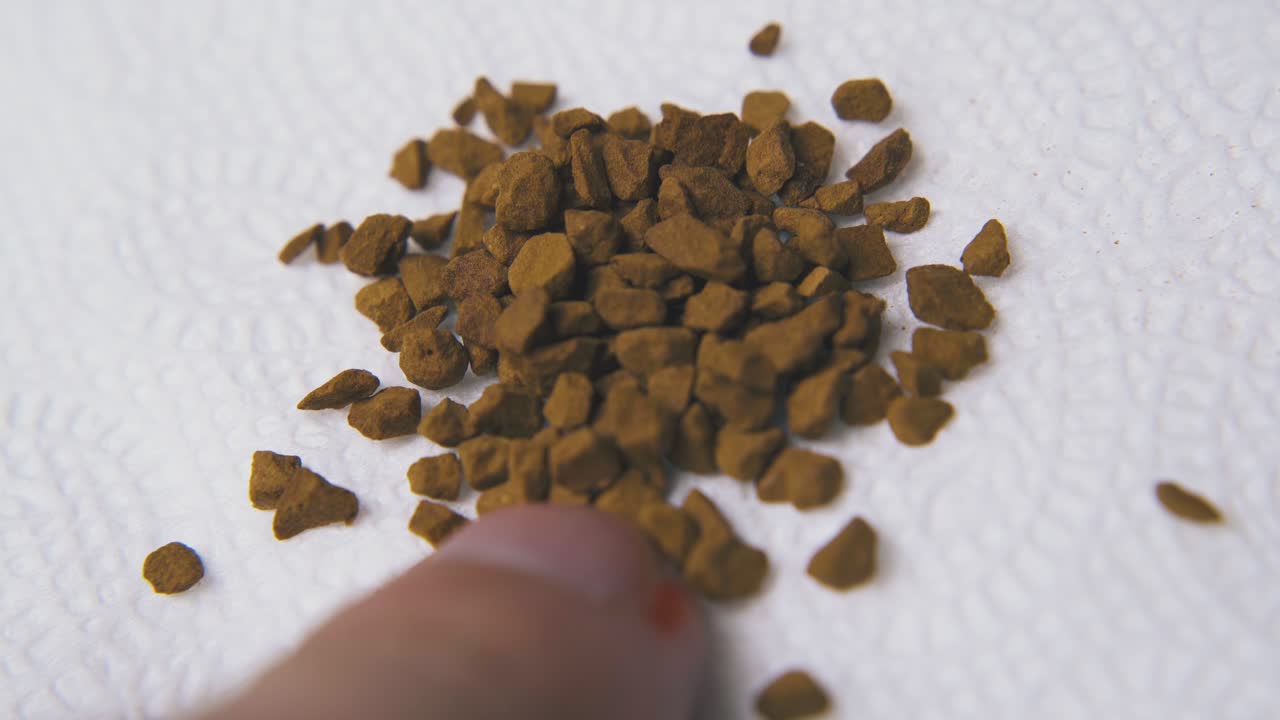eine person gießt braune instantkaffeegranulate auf eine papierserviette