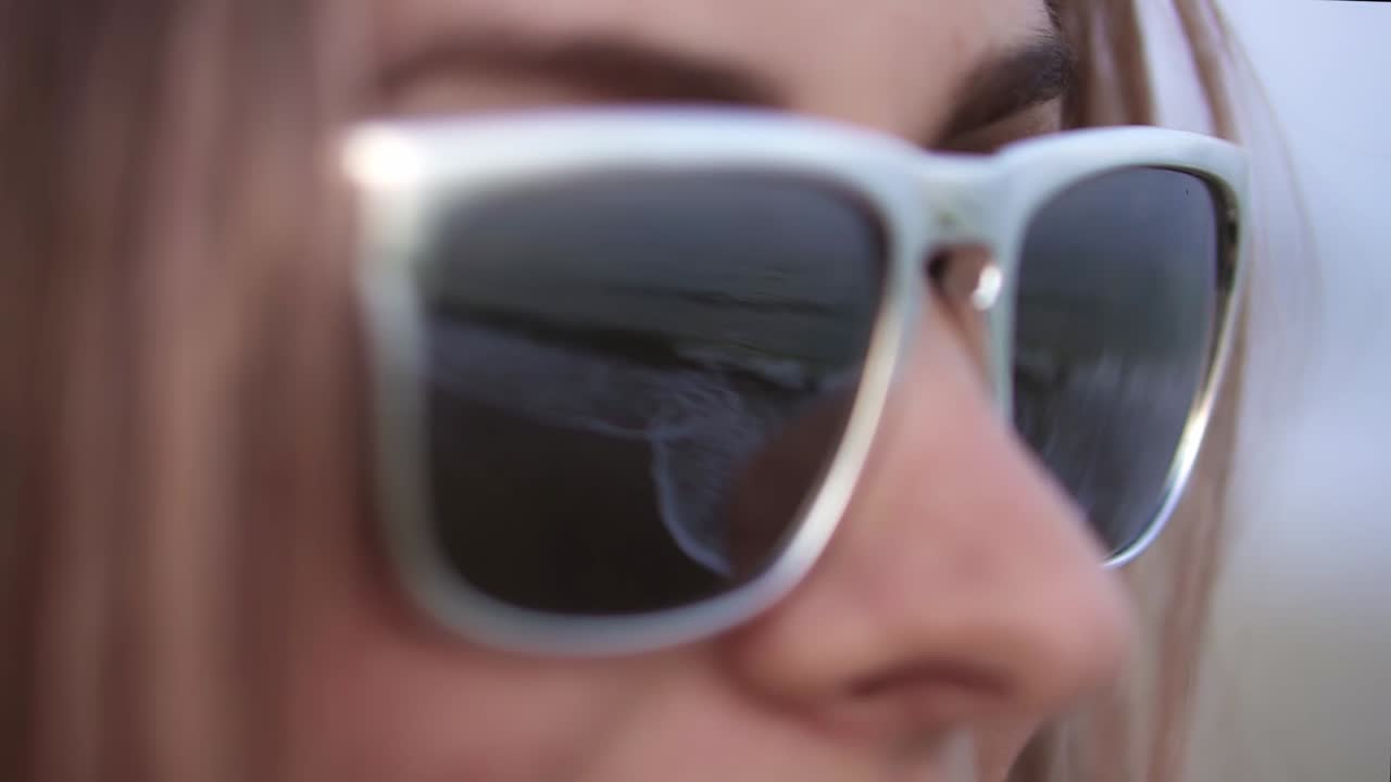 las olas del mar reflejadas en las gafas de sol de una hermosa rubia en la playa