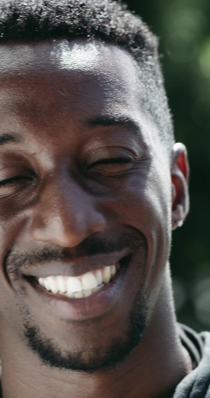 Ritratto ravvicinato di un giovane uomo di colore sorridente all'aperto