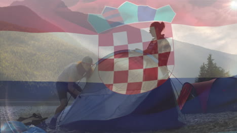 animation of flag of croatia diverse friends setting up tent near river against mountains